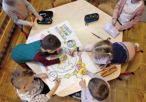 Dzieci z grupy Tropiciele wspólnie kolorują kolorowankę o Prawach Dziecka.