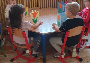 Piątka dzieci z grupy Słoneczka siedzi przy stole i prezentuje wykonane laurki.