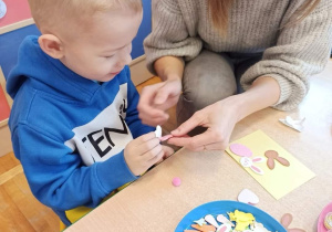 Chłopiec z grupy Biedronki wraz z mamą wykonują kartkę świąteczną.