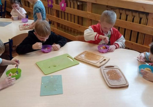 Grupa Pszczółki. Zdjęcie przedstawia czterech chłopców podczas degustacji sałatki owocowej.