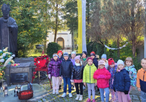 Dzieci z grupy Smerfy pozują przy pomniku Jana Pawła II.