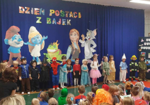 Dzieci z grupy Żabki przebrane w różne postacie śpiewają piosenkę.