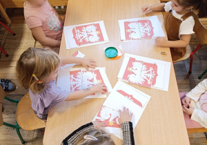 Dzieci z grupy Stokrotki podczas pracy plastycznej- układają puzzle- godło Polski.