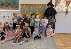 Dzieci z grupy Stokrotki pozują do zdjęcia na tle tablicy, w ręku trzymają czarodziejskie różdżki.