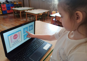 Dziewczynka z grupy „Słoneczka” rozwiązuje zagadki dotyczące bezpieczeństwa w sieci.