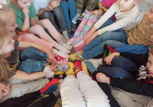 Dzieci z grupy Słoneczka prezentują swoje kolorowe skarpetki.