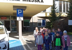 Dzieci z grupy Odkrywcy pozują do zdjęcia przed budynkiem Straży Miejskiej w Bełchatowie.