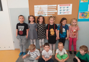 Dzieci z grupy Liski pozują do zdjęcia z piramidą żywienia i instrukcją mycia rąk.