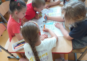 Zdjęcie przedstawia dzieci z grupy Liski wspólnie kolorujące wielką kolorowankę.