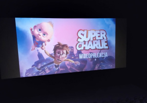 Dzieci siedzą w kinie, czekają na bajkę Super Charlie.