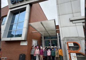 Grupa Motylków pozuje do zdjęcia pod wejściem do Biblioteki Miejskiej