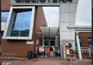 Grupa Smerfów pozuje do zdjęcia pod wejściem do Biblioteki Miejskiej