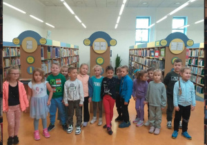 Dzieci z grupy Odkrywcy robią sobie pamiątkowe zdjęcie w wypożyczalni dla dzieci.