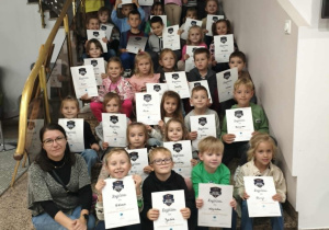 Dzieci wraz z paniami pozują do zdjęcia grupowego z dyplomami.