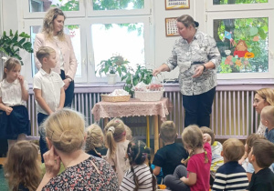 Pani Wicedyrektor bierze do ręki koszyk z lizakami, a dzieci i panie z zainteresowaniem się temu przyglądają.
