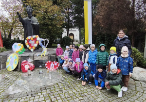 Dzieci z grupy Motylki pozują do zdjęcia przy pomniku papieża Jana Pawła II.