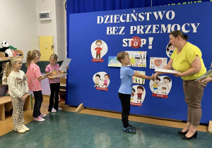 Chłopiec odbiera nagrodę od wicedyrektora za udział w konkursu Dzieciństwo Bez Przemocy.