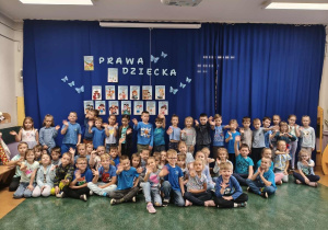 Przedszkolaki z grup najstarszych pozują do zdjęcia na tle dekoracji z informacjami o prawach dziecka.