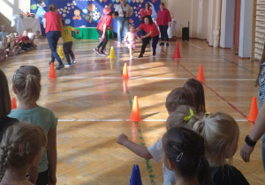 Dzieci przemierzają sportowy tor przeszkód.