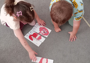 Chłopiec z dziewczynką układają puzzle psa siedząc na dywanie.