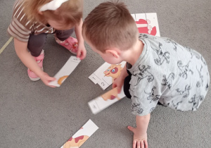 Dwójka dzieci wspólnie układa puzzle przedstawiające psa.