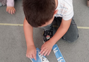 Chłopiec samodzielnie układa puzzle przedstawiające psa.