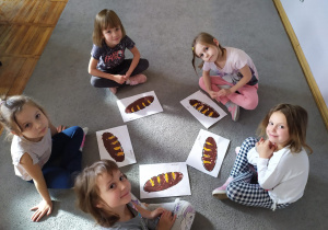 Dziewczynki z grupy Pszczółki prezentują swoje zrobione chlebki jest to praca plastyczna.