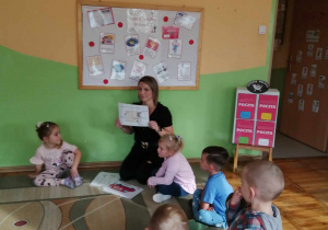 Dzieci z grupy Misie, słuchają nauczycielki która pokazuje i tłumaczy jak należy zaadresować list.