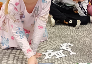 Dziewczynka układ na miseczce papierowe kości zgodnie z cyfrą podaną na kartoniku.