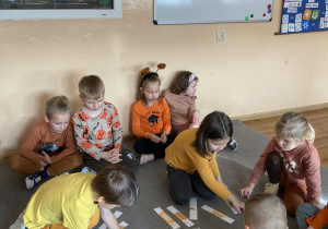 Chłopiec i dziewczynka układają puzzle przedstawiające dynie.