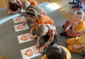 Dzieci układają tyle dyni na planszy ile wskazuje dana cyfra.