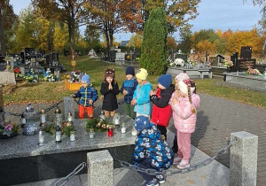 Dzieci z grupy Misie modlą się przed pomnikiem.