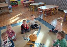 Dzieci z grupy Biedronki siedzą na dywanie z dyniami.