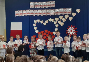 Dzieci śpiewają piosenkę „Co to jest niepodległość” trzymając w rękach serca w barwach ojczystych.