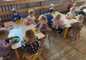Dzieci siedzą przy stolikach, wykonują jeżyki z wykorzystaniem gruszki i wykałaczek.