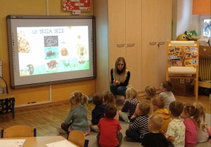 Nauczyciel przedstawia dzieciom prezentację na tablicy interaktywnej związaną z jeżami
