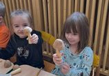 Dziewczynki siedzą przy stoliku w rękach trzymają swoje grzybki.