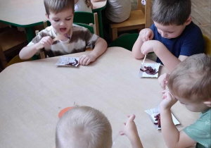Dzieci degustują upieczone frytki przy stoliczkach.