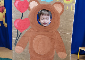 Chłopiec pozuje do zdjęcia w fotobudce z namalowanym misiem.