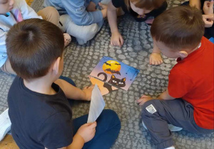Grupa dzieci układa puzzle które przedstawiają czarnego kota