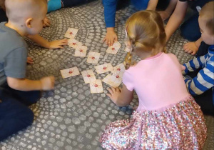 Dzieci siedzą w kole i losują koperty ze swoją wróżbą andrzejkową