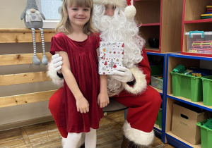 Dziewczynka pozuje do zdjęcia z Mikołajem.