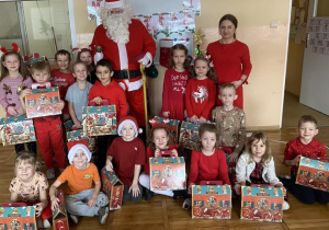 Dzieci z grupy Odkrywcy pozują do zdjęcia z Mikołajem i otrzymanymi prezentami.