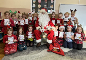 Dzieci z grupy "Smerfy" pozują do zdjęcia z Mikołajem i otrzymanymi prezentami.