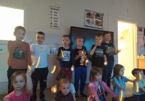 Dzieci śpiewają piosenkę ilustrując słowa trzymanymi w rękach świeczkami (plastikowymi).