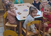 Dzieci siedzą przy stoliku, na stole leżą upieczone pierniczki i pisaki do dekoracji.