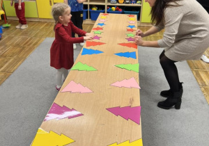 Dzieci ścigają się z rodzicami w ubieraniu kolorowych choinek na stoliku