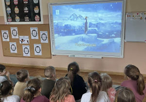 Dzieci oglądają film edukacyjny na temat pingwinów.