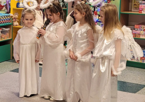 Cztery dziewczynki w strojach aniołków stoją razem, a jeden z nich mówi wierszyk.