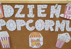 Na tablicy widnieje napis Dzień Popcornu oraz obrazki przestawiające popcorn.